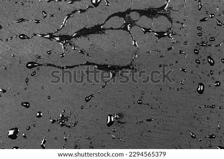 Water drops on dark flat stone surface of basalt or granite background texture