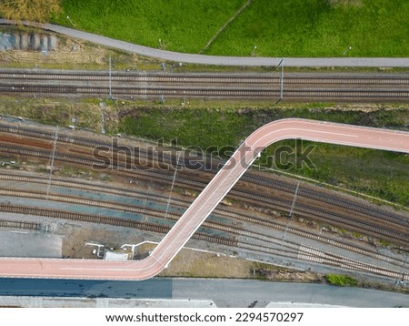 Aerial view shot by a drone of a cyclists and pedestrian bridge over the railroad tracks. High quality photo