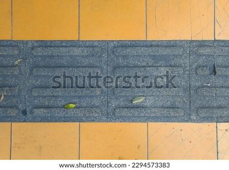 Above symetrical shot of black tactile paving guiding block go on footpath for blind and visually impaired pedestrian. Tactile paving guiding block with long round rectangle pattern that means "Go"
