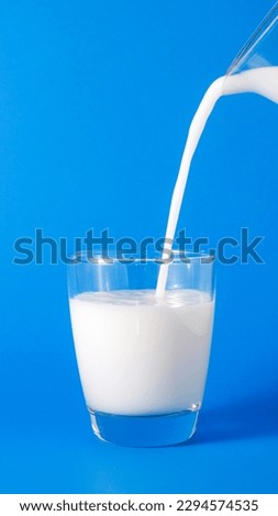 Pour milk. The glass is in the middle of the picture. The milk jug in the upper right is poured from a height.