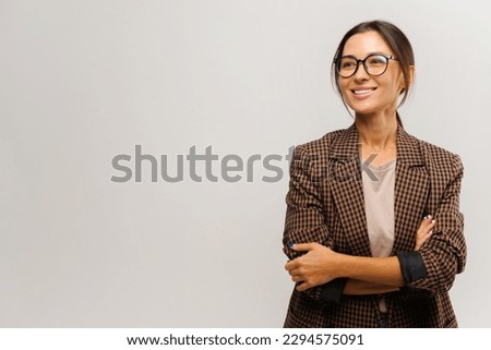 Portrait of cute positive businesswoman wearing formal suit standing with crossed arms and looking away with charming smile. Indoor studio shot isolated on white background Royalty-Free Stock Photo #2294575091