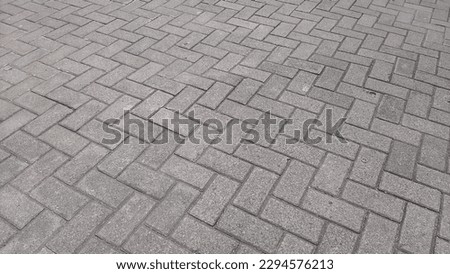 Street Surface Paved Block Textured Like Diagonal Zig Zag Bricks. Gray Rectangular Shaped. Paving Materials Made From A Mixture Of Cement, Sand and Water, So That Their Characteristics Like Mortar