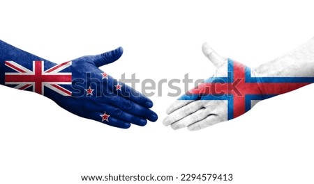 Handshake between Faroe Islands and New Zealand flags painted on hands, isolated transparent image.