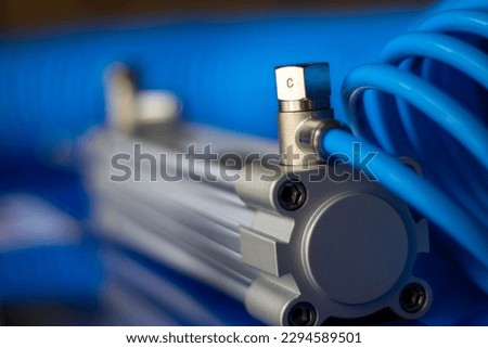 rear head of a pneumatic cylinder on a blue background, with attached flow meter and spiral tube. Royalty-Free Stock Photo #2294589501