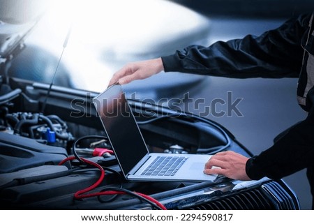 Car diagnostic service close up  computer and modern mechanic in garage. Auto mechanic using computer software for diagnostics engine working and repairing car in a garage. Royalty-Free Stock Photo #2294590817