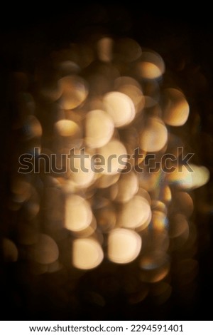 golden bokeh on a dark background. Festive abstract texture, golden bokeh particles and highlights on a dark background. High quality photo. circles of bright lights in in the dark.