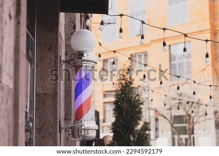 Barber sign and male hairdresser pole or staff mounted on wall. Helix of colored stripes red white and blue
