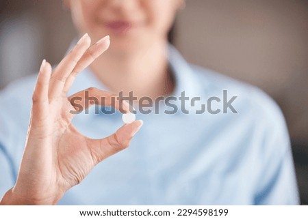 Cropped close up of a mixed race businesswoman holding a medical pill in her hand in a office at wok.Hispanic woman showing a prescribed medicated white pill Royalty-Free Stock Photo #2294598199