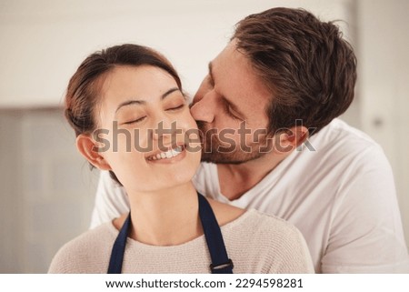 You make me feel loved. Shot of a man kissing his wife on her cheek at home.