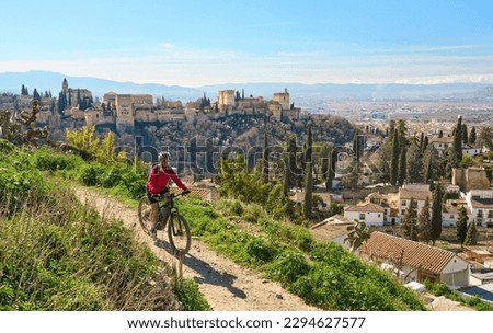 nice active senior woman cycling with her electric mountain bike in Granada below the world heritage site of Alhambra, Granada, Andalusia,  Spain, Royalty-Free Stock Photo #2294627577