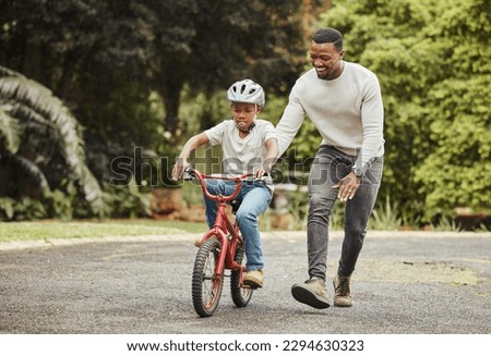 Were standing tall. Shot of an adorable boy learning to ride a bicycle with his father outdoors. Royalty-Free Stock Photo #2294630323