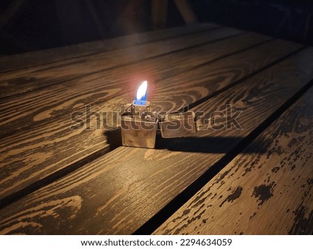 A classic lighter standing on a table in the dark. High quality photo
