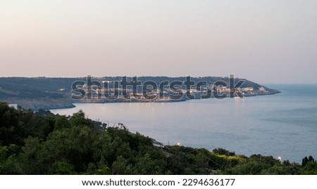 Views of the coast from Armando Perotti square in Castro, Italy. In the distance the city of Santa Cesarea Terme and the calm waters of the Ionian Sea at sunset.