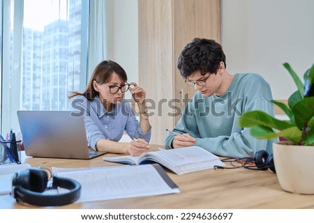 Female tutor teaching college student guy, in classroom at desk Royalty-Free Stock Photo #2294636697