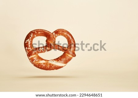 Appetizing traditional Bavarian pretzel baked bun isolated on the bright solid fond plain yellow background. Oktoberfest traditional beer snack style concept Royalty-Free Stock Photo #2294648651