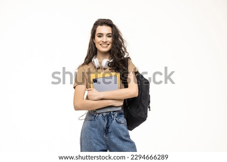 Full length portrait of a smiling young teenage girl wearing backpack and holding pc tablet isolated over white background