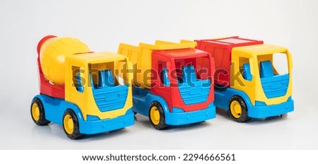 Plastic toy models of construction vehicles on a white background. Truck, concrete mixer, garbage truck.