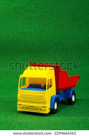 Cargo multi-colored toy car on a green background. Vehicles, outdoor games for children.
