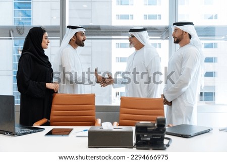 Group of middle-eastern corporate business people wearing traditional emirati clothes meeting in the office in Dubai - Business team working and brainstorming in the UAE Royalty-Free Stock Photo #2294666975