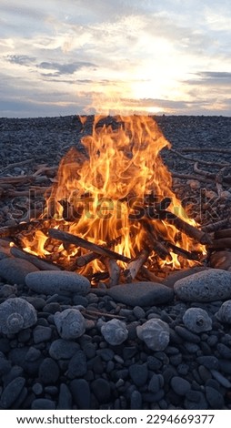 Bonfire on the shore of a pebble beach at sunset