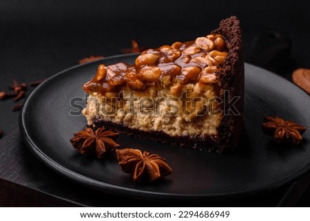 Delicious fresh cheesecake cake or snickers with cream and nuts on a ceramic plate on a dark concrete background