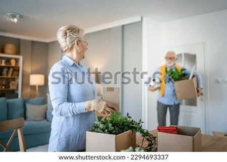 family senior couple man woman husband and wife pensioner grandfather grandmother moving in new apartment taking their stuff belongings and plants in or out of boxes packing or unpacking real people Royalty-Free Stock Photo #2294693337