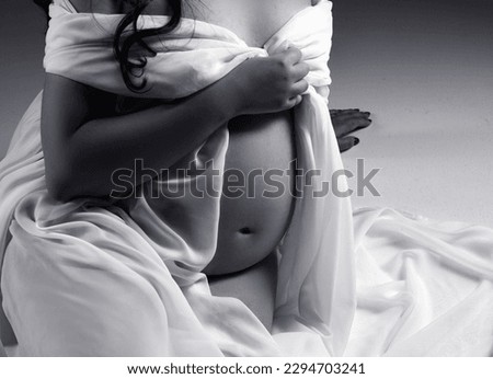 Pregnant woman in a white dress. Pregnant silhouette. Pregnant belly close up. Person with a belly.