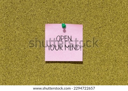 Open your mind text on pink post-it paper pinned on bulletin cork board. This message can be used in business concept about mindset.