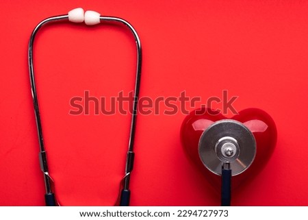 Stethoscope and red heart on red background. cardiology concept. Space for text. Royalty-Free Stock Photo #2294727973