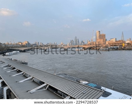 View over the River Thames from the Hungerford Bridge and Golden Jubilee Bridge towards St Paul’s Cathedral and The Shard in early evening. Uber  Boats are on the water
