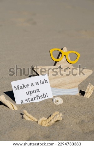 MAKE A WISH UPON A STARFISH text on paper greeting card on background of funny starfish in glasses summer vacation decor. Sandy beach sun coast. Holiday concept postcard. Getting away Travel
