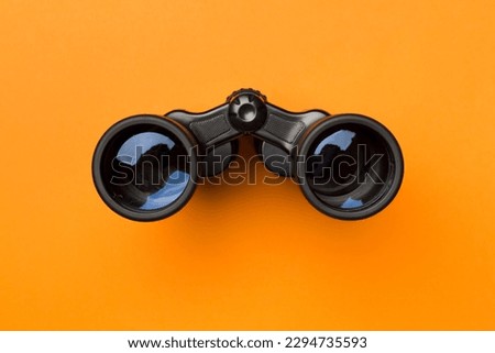 Black binoculars on color background. Top view Royalty-Free Stock Photo #2294735593
