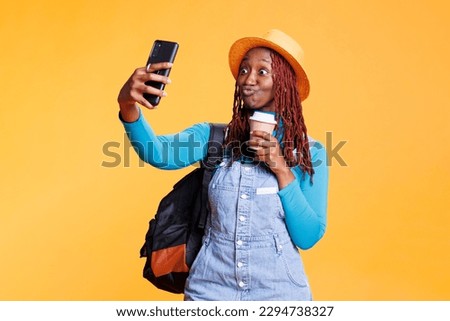 Joyful woman taking photos on vacation holiday, feeling excited with coffee on international journey in studio. Young person having fun with pictures, urban adventure with images.