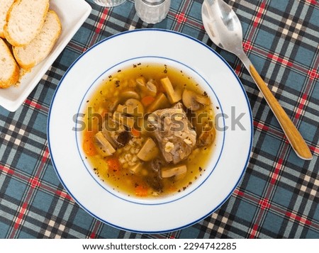 Hearty homemade soup with forest mushroom, pork, vegetables and pearl barley. Russian cuisine..