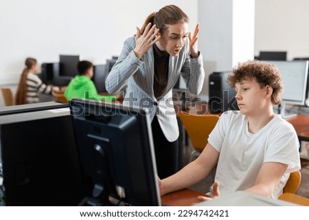 Teacher is dissatisfied with student during classes in the computer class of the school Royalty-Free Stock Photo #2294742421