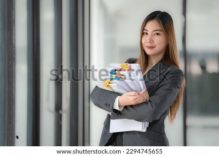 Asian businesswoman standing and holding many documents in an office.