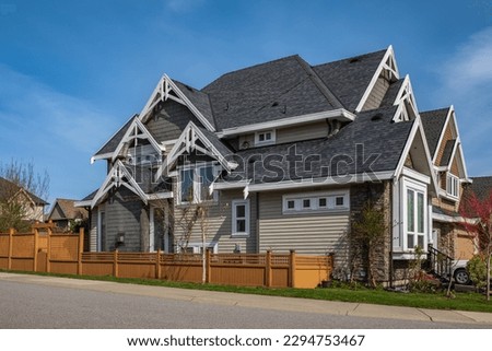 Real Estate Exterior Front House on a sunny day. Big custom made luxury house with front yard in spring. Roof shingles on top of the house. Dark asphalt tiles on the roof, black shingles, roof tile Royalty-Free Stock Photo #2294753467