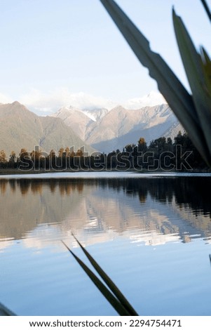 Landscape of a mountain lake with mountains and a glacier in New Zealand. The mountains are reflected in the lake.