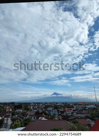views of Mount Merapi and Merbabu whose peaks are covered with wisps of clouds above the residents' housing