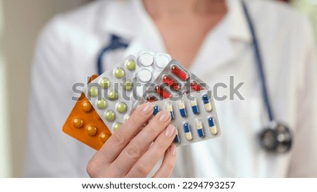 Female doctor with stethoscope holds blister packs of pills and vitamins in hand. Specialist prescribes effective medications for disease treatment Royalty-Free Stock Photo #2294793257