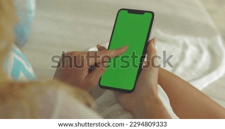 A woman holds a mobile phone in her hands. Use green screen for close-up copy space.