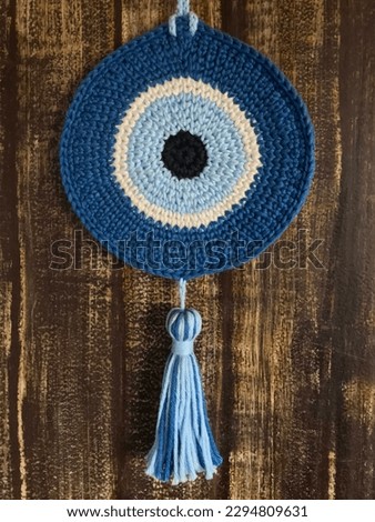 Crochet greek eye mandala hanging on wood textured wall