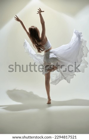 Modern ballet dancer. A young graceful ballerina in a delicate white dress dances with expression. Full-length studio portrait. Choreography. 