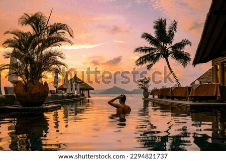 Luxury swimming pool in tropical resort, relaxing holidays in Seychelles islands. La Digue, Young man during sunset by swimpool Seychelles Royalty-Free Stock Photo #2294821737