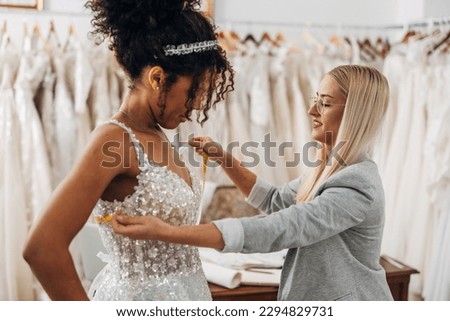 Tailor measures chest circumference on a beautiful African American bride Royalty-Free Stock Photo #2294829731