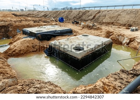 Connecting a trench drain to a concrete manhole structure at construction site. Concrete pile in formwork frame for construct stormwater and underground utilities, pump stations, sewers pipes.