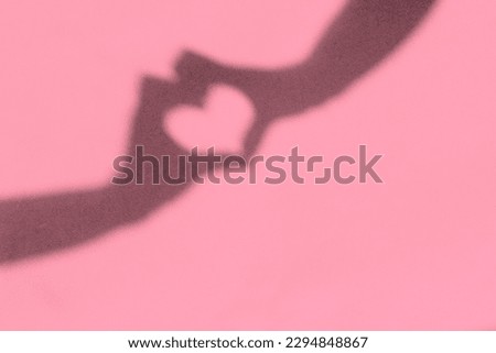 Shadow of hands with heart shape on pink background, copy space, love concept
