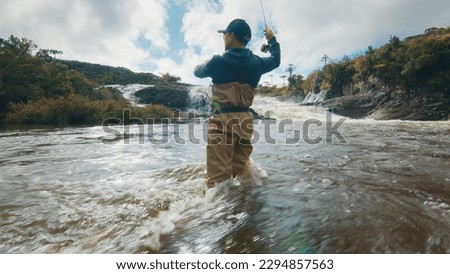Fly fishing. Fisherman in waders fishing on the rapid river Royalty-Free Stock Photo #2294857563