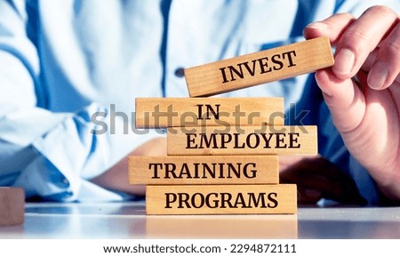 Close up on businessman holding a wooden block with "Invest in employee training programs" message Royalty-Free Stock Photo #2294872111