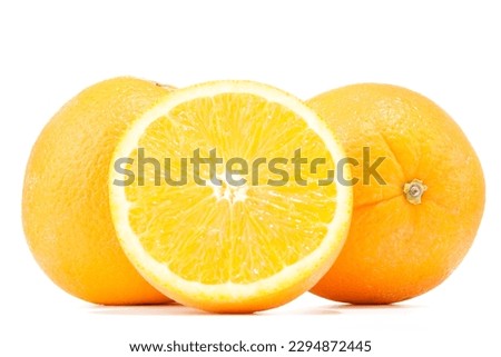 Several fresh and large organic oranges and an orange cut in half on a white background. Front view. Isolated on white. Close up. Studio shot. 